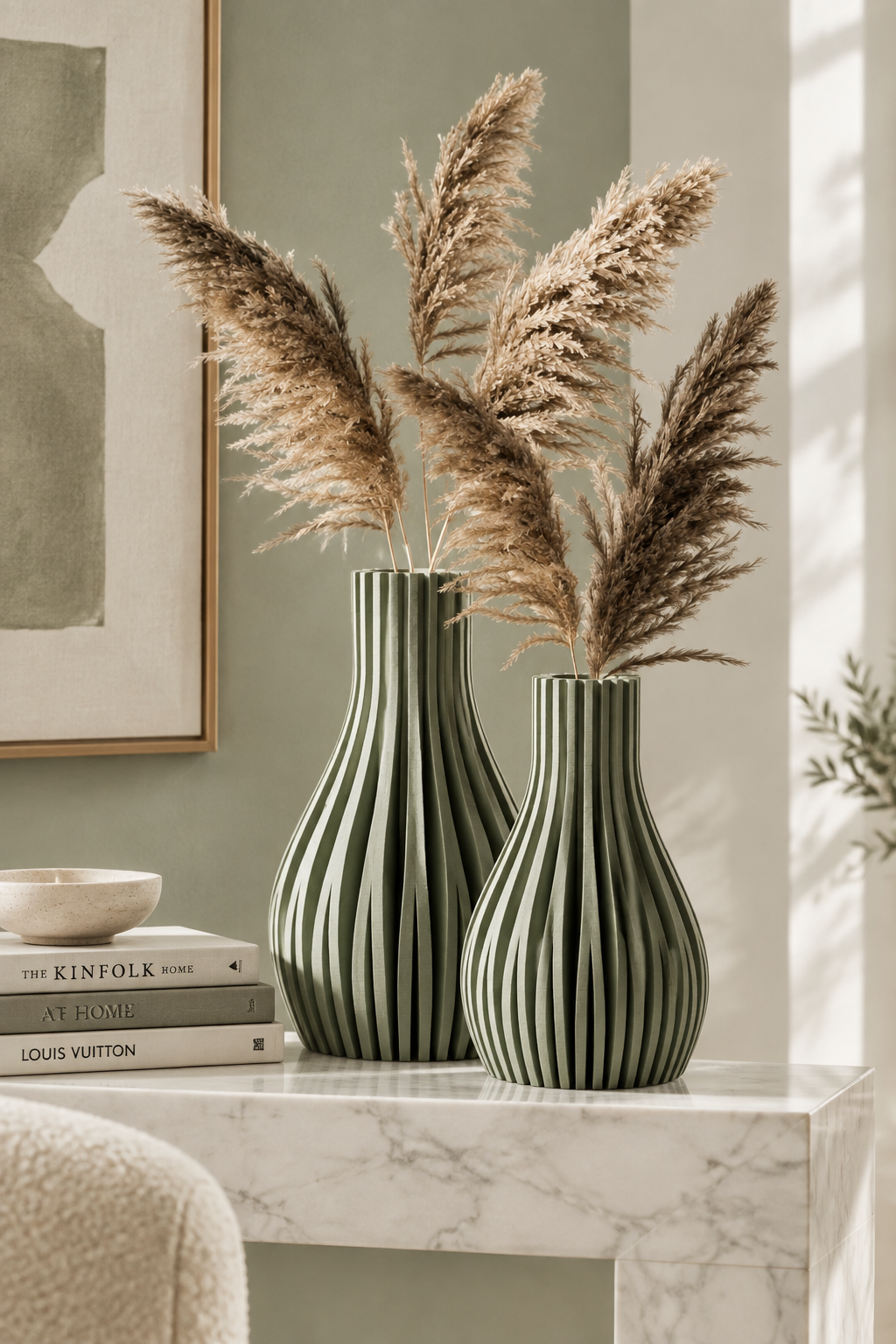 Sage green striped Willow vases with pampas grass on a marble console table with art books